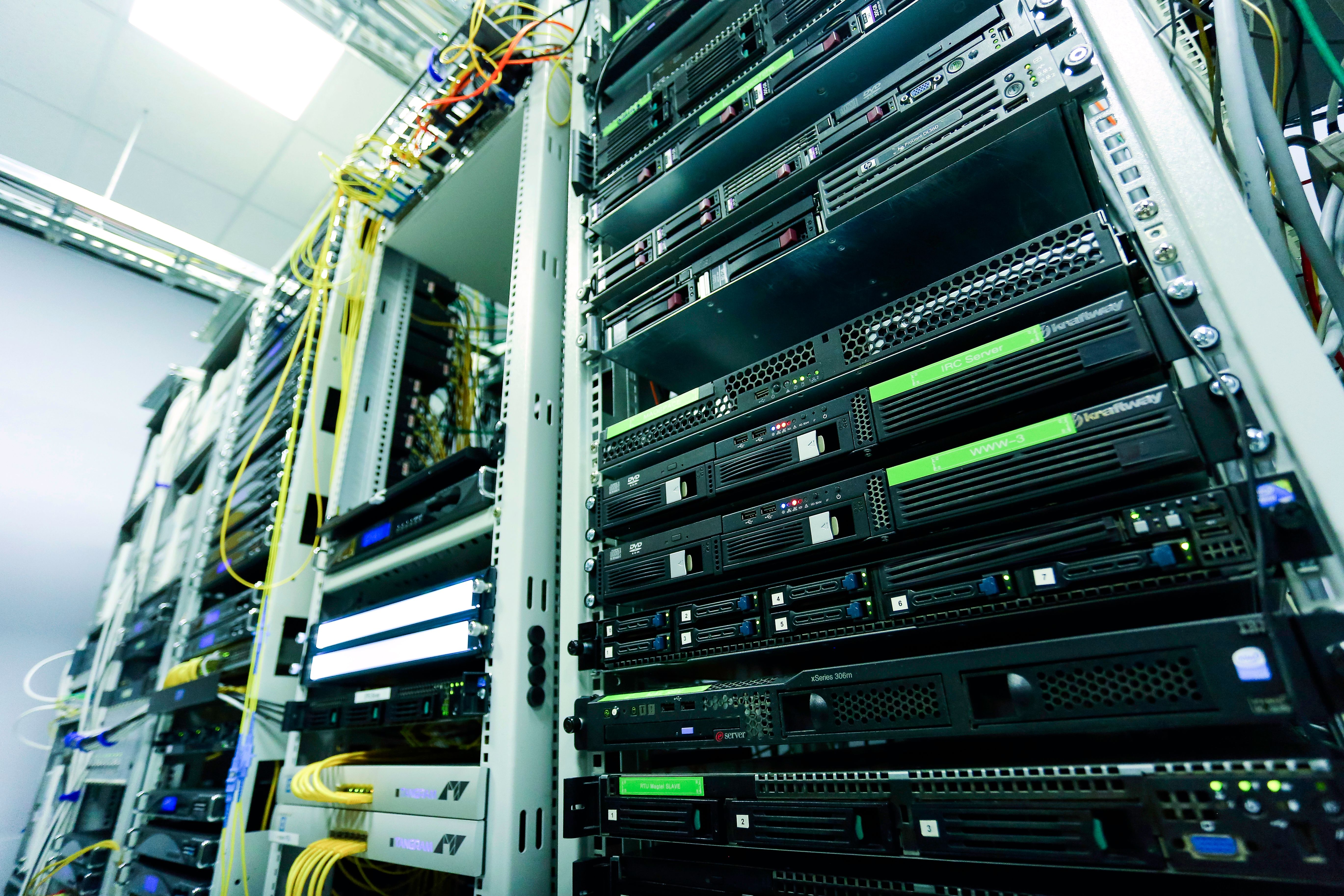 Rows of rack-mounted servers and network equipment inside a brightly lit data center.